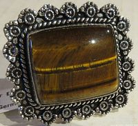 Close-up top view of the large rectangular Tiger Eye gemstone set in an ornate floral-patterned German Silver bezel with rope detailing.