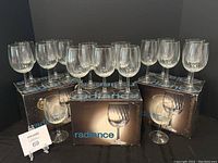17 clear wine glasses with short stems arranged on and around three Radiance branded boxes, showing quantity and packaging.