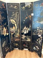 Front view of two black lacquered wooden panels with painted scenes of traditional Chinese figures, florals, and nature inlays