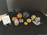 Collection of all eight paperweights displayed on black cloth showing various designs and sizes together