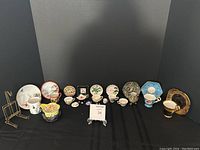 Full view of assortment including 13 decorative mini teacups with plates arranged on black background along with three gold-tone cup displays