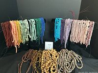 Multiple rows of beaded strands displayed on two horizontal stands and loose bead piles in front