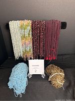 Shows bundled strands of beads wrapped on a black rod and loose strands below