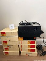 Stack of eleven Kodak Carousel Transvue 140 slide trays and Honeywell projector on top with power cord ready.