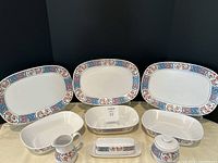 Full set of Noritake china serving items including platters, bowls, cream and sugar set, and butter dish displayed together showing pattern and quantity of pieces.
