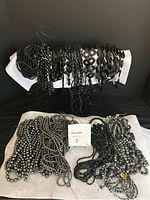 Overview photo showing multiple black bead strands on white display cloth with different shapes and sizes visible.