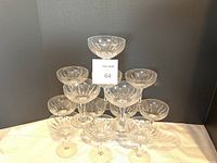 Thirteen Stuart crystal champagne glasses arranged in a pyramid shape, showing etched starburst pattern and coupe shape.