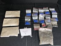 Overview photo showing all bead packs and smaller bags, arrangement on black fabric background.