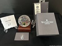 Crystal globe paperweight on wooden stand with original box and authentication materials visible.