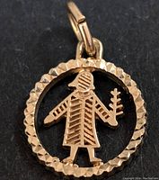 Close-up of the front of the 10K gold figure pendant showing detailed texture and design.