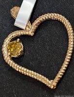 Close-up detailed photo of the 14K gold open heart pendant with yellowish lab diamond gemstone set within the top-left part of the heart.