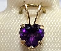 Close-up of the heart-shaped deep purple amethyst stone set with four gold prongs in 14K gold.