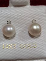Front view of pair of 14K gold stud earrings with white freshwater pearls and small diamonds on top, displayed on a white padded holder marked '14KT GOLD'.