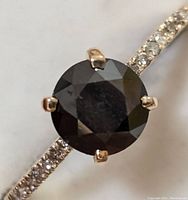 Close-up of round black diamond and adjacent white accent diamonds on band