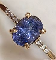 Close-up of oval tanzanite center stone and adjacent diamond accents at an angle
