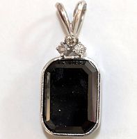Front view of pendant showing emerald-cut black diamond and three round white diamonds