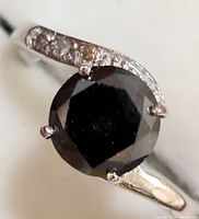 Top-left angle close-up of round black diamond center with adjacent white diamond accents.