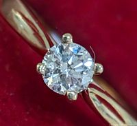 Close-up of round diamond in six-prong setting on polished gold band