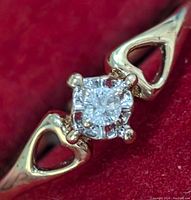 Close-up front view of the ring showing the diamond and heart-shaped cutouts on band sides.