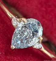 Top view of pear‐shaped lab diamond ring on red background