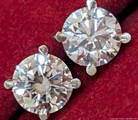 Front view of both round brilliant cut diamond studs on red background