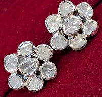 Close-up view of two sterling silver earrings with multiple rough natural diamonds arranged in a floral cluster pattern on red velvet background.