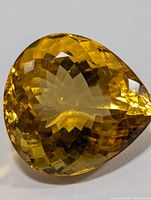 Front view of the faceted pear-shaped citrine gemstone with vibrant golden-yellow color and checkerboard cut.