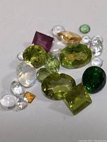 Loose faceted gemstones in various colors and cuts on a white surface.