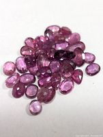 Loose faceted ruby gemstones in various shapes and sizes on white background