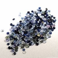 Close up photo of a pile of loose genuine sapphire gemstones in various colors and sizes on a white background.