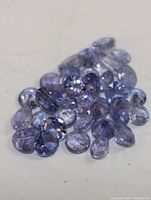 Close-up of multiple loose genuine tanzanite gemstones showing blue-violet colors and faceted cuts.