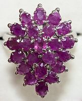 Front view of silver ring showing floral cluster of multiple oval ruby stones.