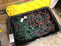 Plastic bin filled with multiple red and green bulb Christmas lights, showing the amount and condition of the bundled lights inside.