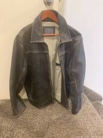 Front view of coat on hanger showing zip closure and exterior pockets