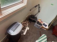 Royal 150MX crosscut shredder, power bars, halogen adjustable desk lamp, assorted office supplies in container, all on carpeted floor near window