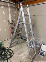 Front view of the Caradon aluminum step ladder standing in a garage, showing the overall structure and six wide steps on each side.