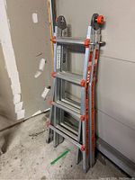 Closed ladder leaning against garage wall showing overall condition