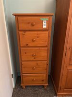 Front view of the five drawer tallboy dresser in natural wood with wood knobs.