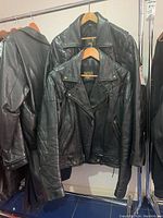 Overview of two black leather jackets on rack, one quilted and one smooth