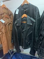 Two leather jackets hanging on a rack, one black and one brown.