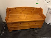 Front view of the wood storage bench showing the flip-lid top and backrest.