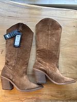 Side view of brown suede leather boots showing the heels and height.