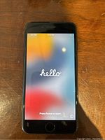 Front view of black iPhone SE 2020 displaying English 'hello' setup screen with no SIM notification.