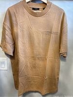 Full front view of khaki Jack and Jones T-shirt hung on hanger showing color, shape, and front print detail.