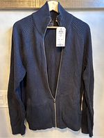 Front view of blue ribbed knit cardigan with full zip and collar, showing tag attached.