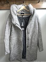 Front view of a light grey women's large wool coat on a hanger showing texture, style, and shape