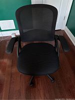 Front view of black office chair showing mesh backrest, cushioned seat, and armrests.