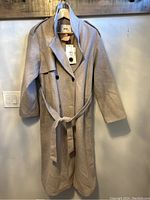 Full view of the light beige double-breasted women's coat hanging on hanger showing overall condition and design.