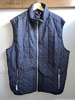 Front view of men's sleeveless puffy vest in navy blue, showing full zip and two zippered pockets.