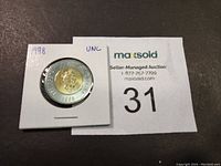 Obverse side of the 1998 Canadian $2 coin showing Queen Elizabeth II, housed in a white protective holder with year and condition labeled 'UNC'.